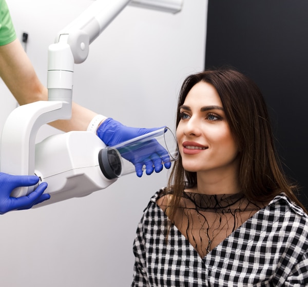 Woman receiving dental treatment from dentist wearing blue gloves in modern dental office.