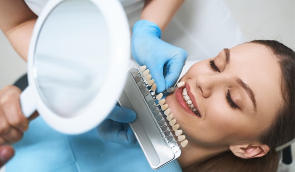 Dentist holding mirror during oral examination of smiling patient in dental office